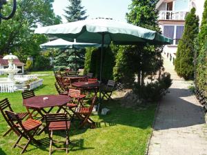 a group of tables and chairs under an umbrella at Villa Vivian in Szczecin