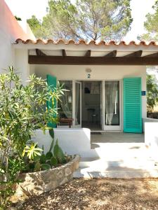 a house with a blue door and a porch at Cabaña Cala Saona in Sant Francesc Xavier