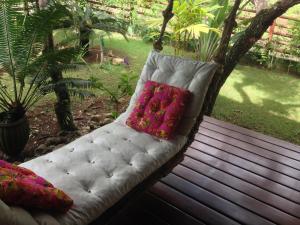 um sofá branco com duas almofadas sentadas num alpendre em Bangalô alto do Mucugê em Arraial d'Ajuda