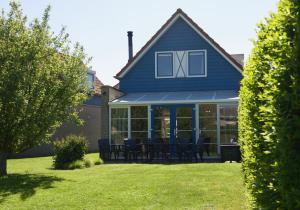 Una casa azul con una mesa y sillas en un patio. en Antibes 252 - Kustpark Village Scaldia, en Hoofdplaat