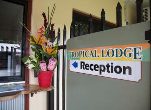 a hospital lodge reception sign next to a door with flowers at Tropical Lodge in Innisfail
