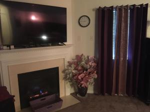 sala de estar con chimenea, TV y reloj en Premier National Harbor House en Fort Washington