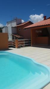 a blue swimming pool in front of a house at Guest House Paraiso Pataxos in Porto Seguro