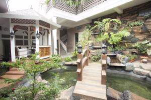 ein Haus mit einem Teich im Hof in der Unterkunft Huis Van Gustafine Floor 1 in Malang