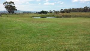 a field of grass with a pond in the middle of it at Bass Coast Country Cottages in Bass