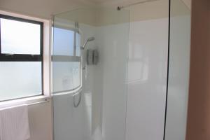 baño con ducha y puerta de cristal en Kiwi Court Motel, en Hawera
