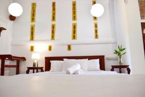 a bedroom with a bed with white sheets and yellow accents at Villa Scĕnns in Sangkhla Buri