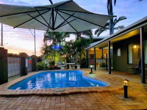 
a patio area with a pool table, chairs and umbrellas at Rockhampton Palms Motor Inn in Rockhampton
