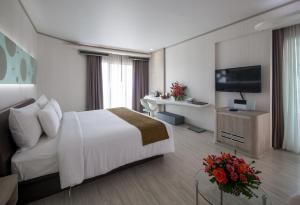 a hotel room with a bed and a television at Pattaya Discovery Beach Hotel - SHA Extra Plus in Pattaya