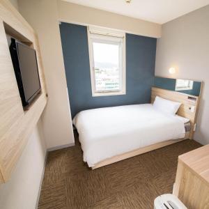 a bedroom with a white bed and a window at Super Hotel Okinawa Nago in Nago