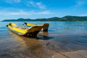 un barco amarillo sentado en la orilla de un cuerpo de agua en Refron du Mar Pousada Paraty, en Paraty