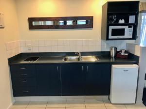 a kitchen with a sink and a microwave at Claremonte Motor Lodge in Hastings