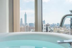 a bath tub in a bathroom with a view of a city at amba Taipei Songshan in Taipei