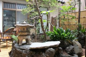 um jardim com uma lanterna de pedra, uma mesa e cadeiras em Juyoh Hotel em Tóquio