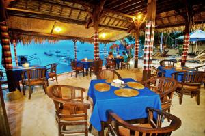 a restaurant with tables and chairs with a view of the water at Lumbung Bali Huts in Nusa Lembongan