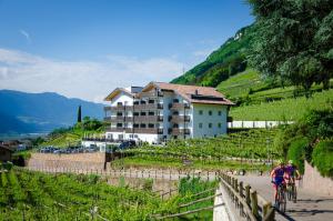 una persona che va in bicicletta lungo una strada accanto a un edificio di Vineus Tramin a Termeno