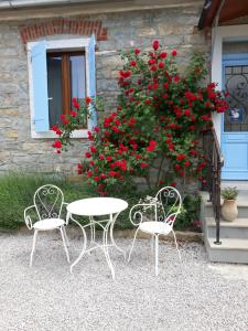 two chairs and a table in front of a house with red flowers at Apartment Pod Kostanji in Osp