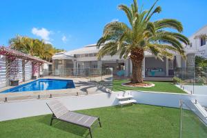 a house with a palm tree and a swimming pool at Coastal Elegance in Gold Coast