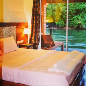 a bedroom with a large bed and a window at Koh Mueangkarn Paradise View Resort in Sai Yok