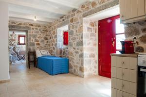 a kitchen with a red door and a stone wall at Limeni Villa in Limeni