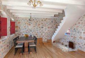 jadalnia z drewnianym stołem i kamienną ścianą w obiekcie Limeni Villa w mieście Limeni