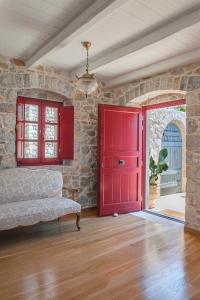 Cette chambre est dotée d'une porte rouge et d'un mur en pierre. dans l'établissement Limeni Villa, à Limeni