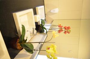 baño con lavabo, espejo y flores en Kyriad Hotel Airport Jakarta, en Tangerang