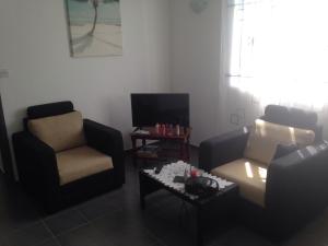 a living room with two chairs and a tv at Villa FRANCOISE in Pereybere
