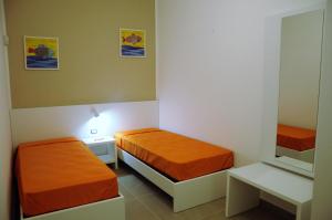een kleine kamer met twee bedden en een spiegel bij Punta Prosciutto GMA Tourism in Porto Cesareo