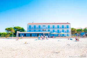 a group of people on a beach with a blue building at Hôtel George Sand in La Seyne-sur-Mer