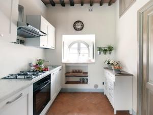 a kitchen with white cabinets and a clock on the wall at la Senesina in Monteriggioni