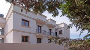 a large white building with windows and trees at Morello Beach Hotel in Marina di Pescoluse