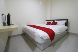 Dormitorio blanco con cama con almohadas rojas en RedDoorz Plus near Mall Ciputra Jakarta, en Yakarta