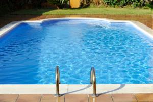 uma grande piscina azul com duas pegas metálicas em Aparthotel Marsol em Castelldefels