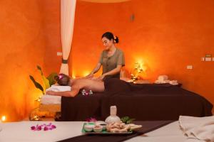Eine Frau, die einer Frau eine Massage auf einem Bett gibt. in der Unterkunft Mai Khaolak Beach Resort & Spa - TUIBLUE Mai Khaolak in Khao Lak
