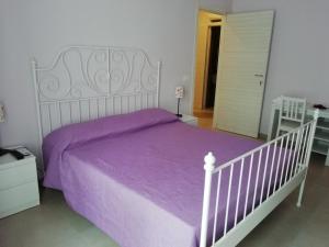 uma cama branca com lençóis roxos num quarto em Il gelsomino em Scicli