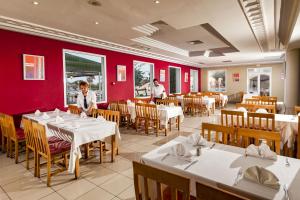 un restaurant avec des tables et des chaises blanches et des murs rouges dans l'établissement Hotel Club El Borj, à Mahdia