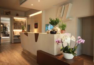a lobby with a counter with flowers on it at Hotel Lucerna in Castiglione della Pescaia
