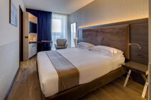 una camera d'albergo con un grande letto e una scrivania di Best Western Plus Hotel Farnese a Parma