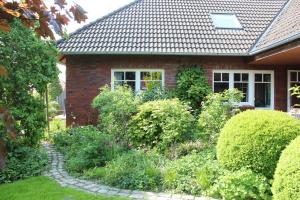 een tuin voor een huis met struiken bij Ferienwohnung Lüntjenüst in Upgant-Schott