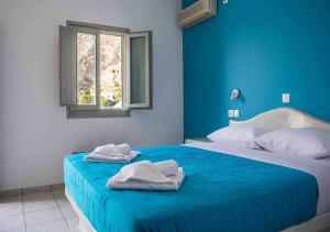 a blue bedroom with two beds with towels on them at Sail Inn Studios & Apartments in Kamari