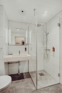 a bathroom with a shower, sink, and toilet at Clarion Collection Hotel Grand Bodø in Bodø