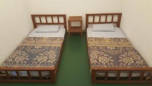 two twin beds in a room with green floors at Tabun Homestay in Miri