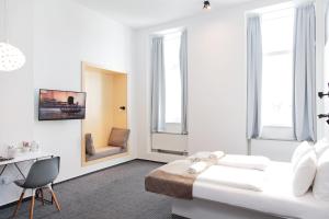 a white room with a bed and a desk and windows at Maverick Budapest Soho in Budapest
