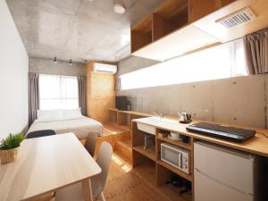 a room with a bed and a kitchen with a table at Smi:re Stay Oshiage in Tokyo