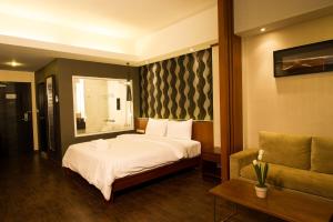 um quarto de hotel com uma cama e um sofá em Inn Residence Serviced Suites - SHA Extra Plus em Praia de Jomtien