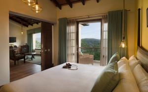 a bedroom with a large bed with a large window at The Tamara Kodai in Kodaikānāl