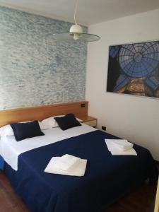 Un dormitorio con una cama azul y blanca con toallas. en Casa Vacanza Bergamo Centro en Bérgamo