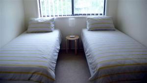 two beds in a small room with a window at BARRELS AT BOOMERANG in Blueys Beach
