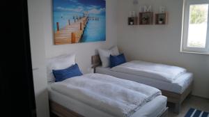 duas camas num quarto com uma pintura de cais na parede em Schönes Ferienhaus direkt am Meer em Stomorska
